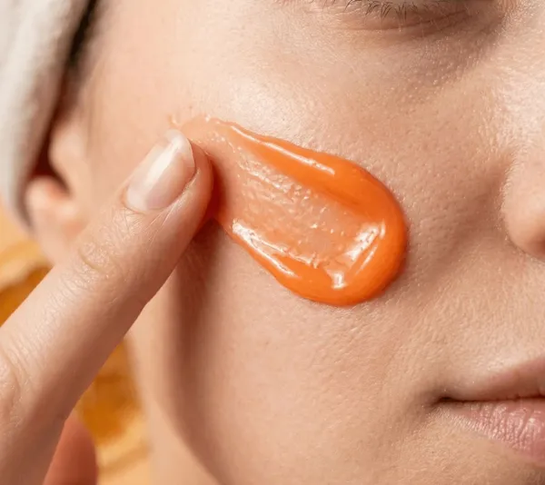 Vrouw brengt de zachte Orange Cream aan op haar wang